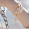 Close-up of a wrist wearing the Clear Quartz Bracelet with Evil Eye from the Elementa Collection, featuring raw crystal beads for clarity against a bright background.