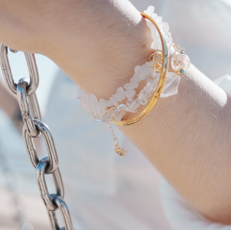 Close-up of a wrist wearing the Clear Quartz Bracelet with Evil Eye from the Elementa Collection, featuring raw crystal beads for clarity against a bright background.