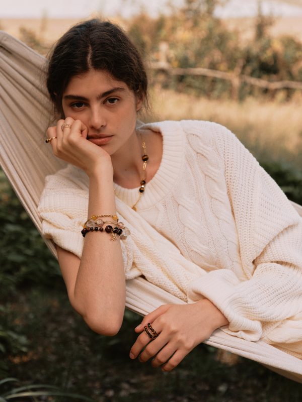 Woman wearing a set of Tiger's Eye and Red Agate jewelry including a necklace and bracelets for grounding and stability.