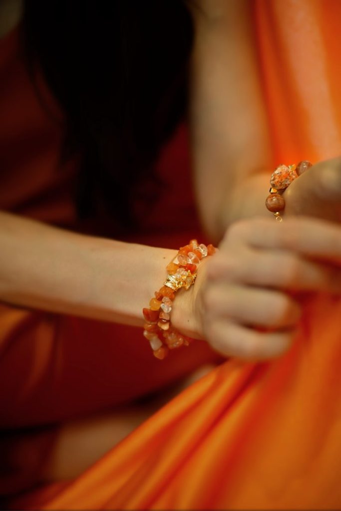 Detail shot of South Red Agate and Sunstone beaded bracelets symbolizing passion, vitality, and the Fire element.