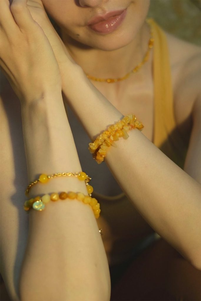 Woman wearing stacked Citrine and Yellow Jade crystal bracelets for abundance, joy, and Solar Plexus alignment.